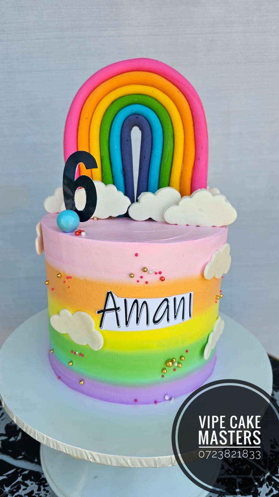 Pastel rainbow striped sixth birthday cake with fondant rainbow, clouds and Amani name plaque