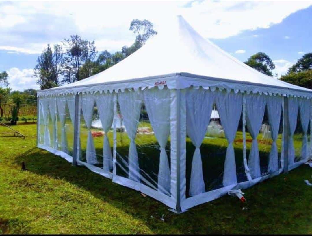 White pagoda marquee with sheer curtain walls pitched on a green lawn