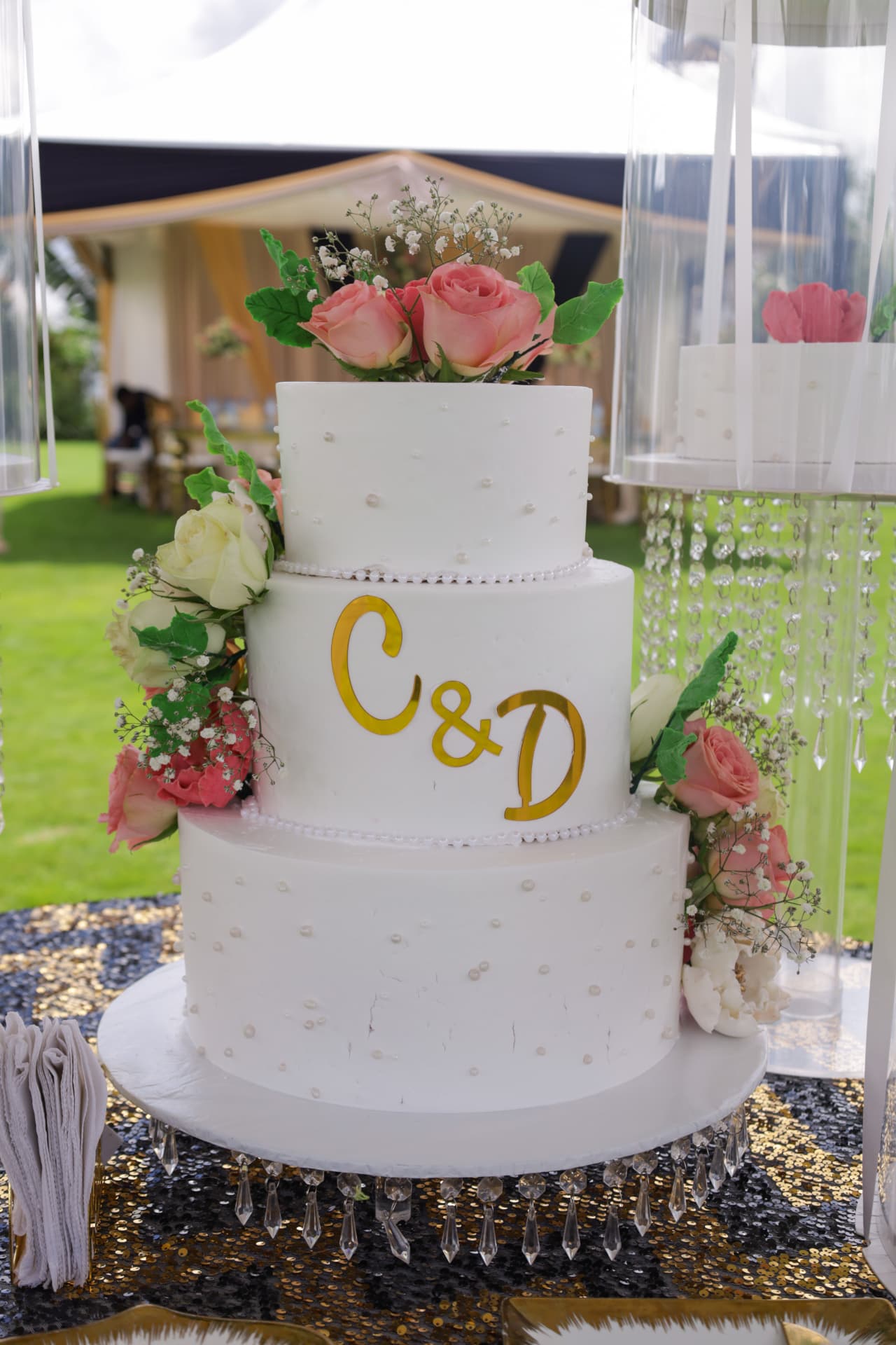 Close view of a white three-tier wedding cake decorated with pink and white flowers
