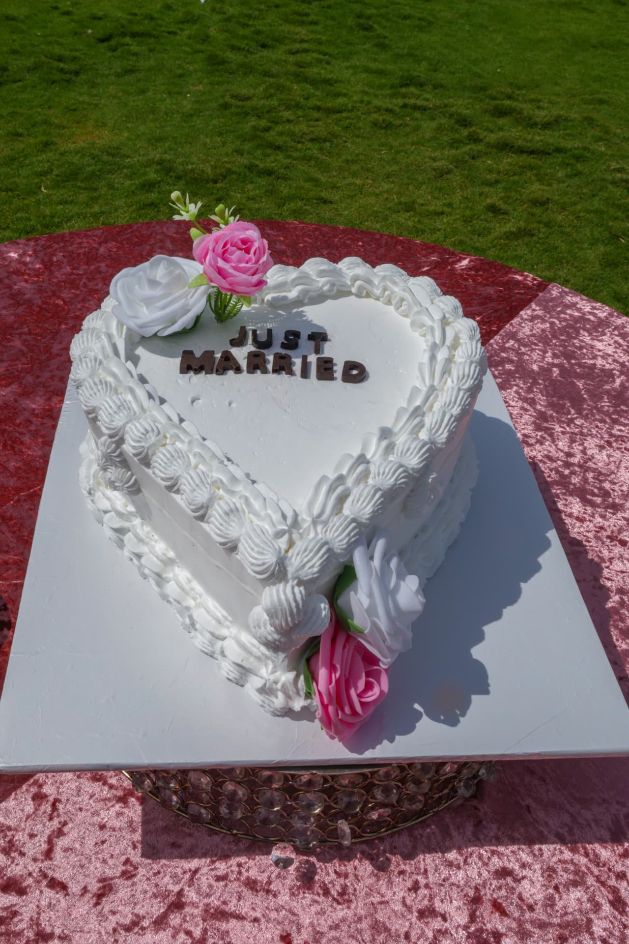 White heart-shaped just married cake with piped borders and pink roses
