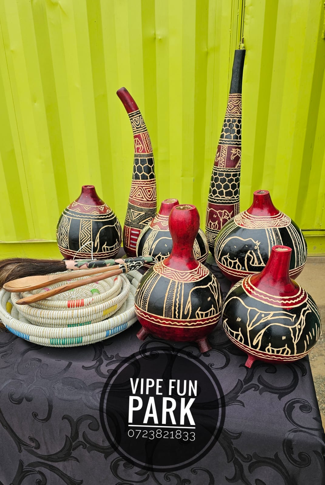 Decorated red and black gourds, beaded pieces and traditional accessories displayed on a table