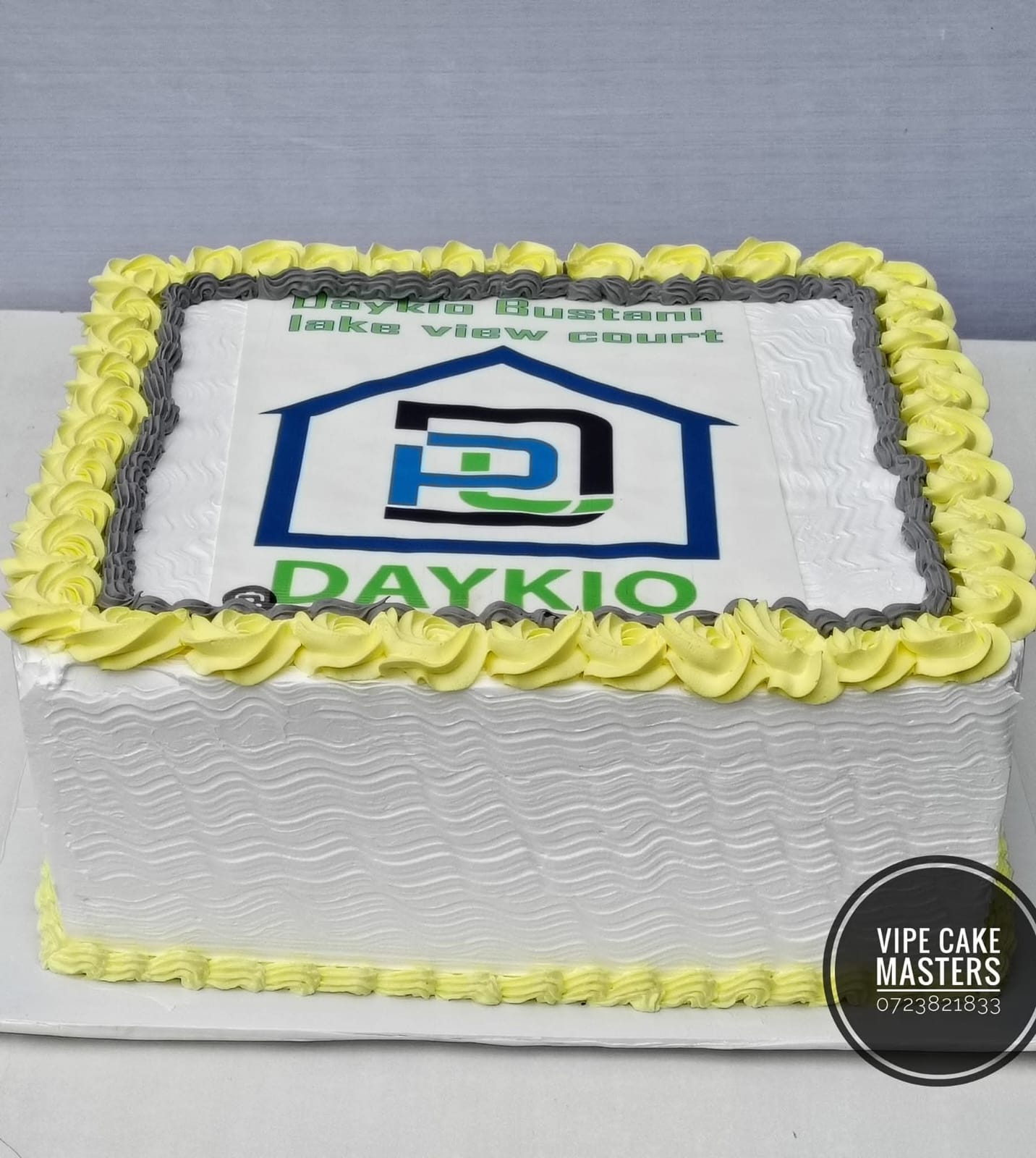 Rectangular corporate cake for Daykio Bustani Lake View Court with house logo and yellow-grey rose border
