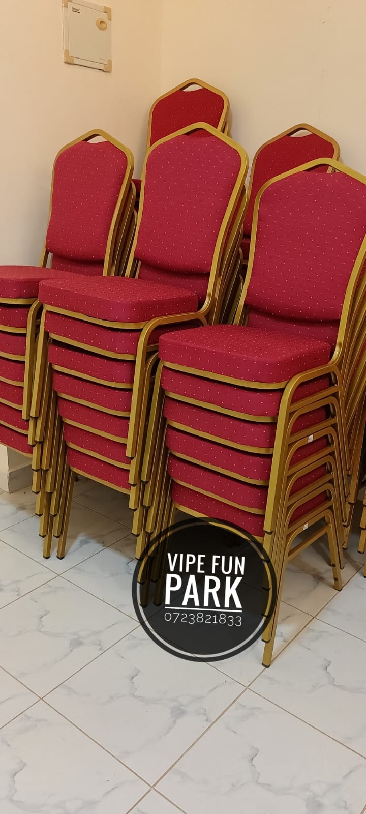 Stacked red upholstered banquet chairs with gold metal frames indoors