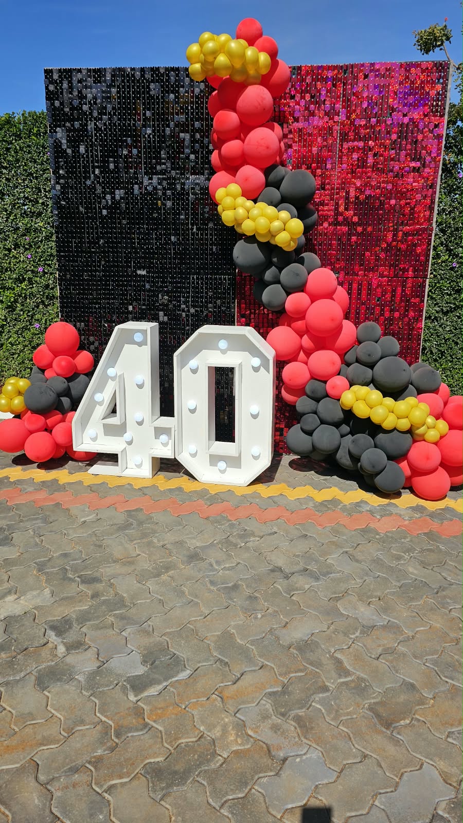 Red, black and gold balloon installation with sequinned backdrop and illuminated number 40