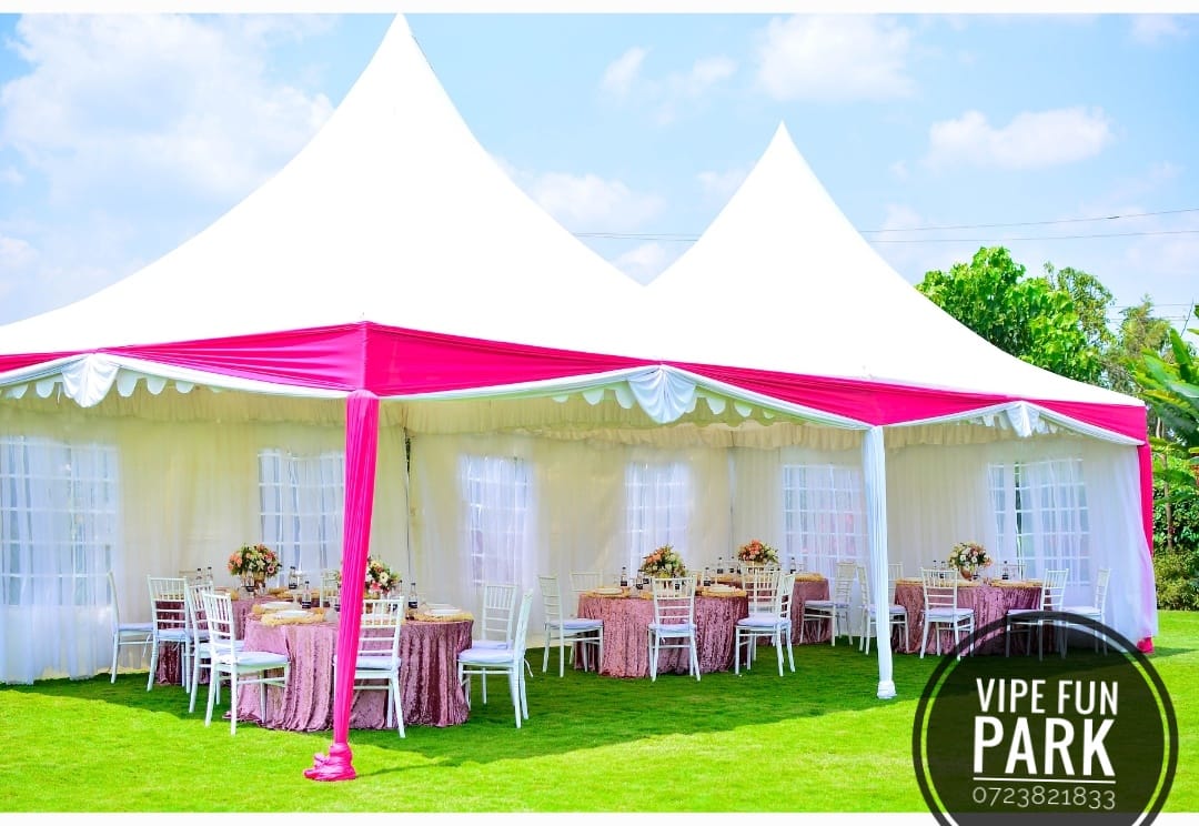 White peaked marquee with bright pink draping, round tables and white chairs on the Vipe lawn