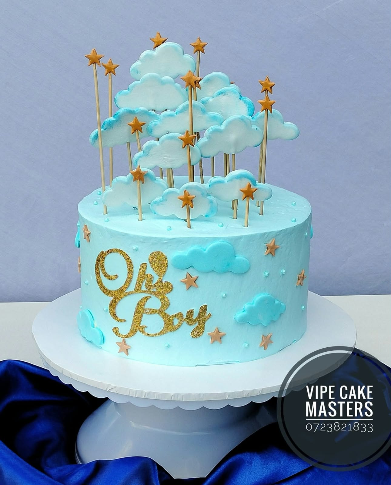 Baby blue Oh Boy cake with white clouds and gold stars on tall sticks