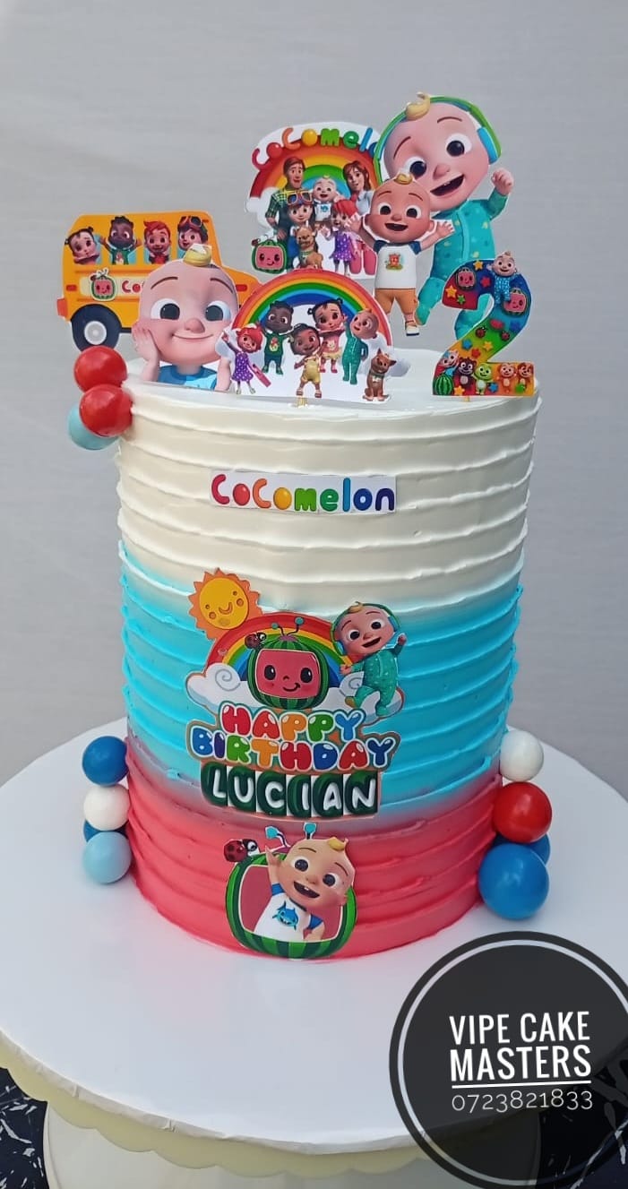 White, blue and pink ribbed Cocomelon second birthday cake with character toppers and Happy Birthday Lucian