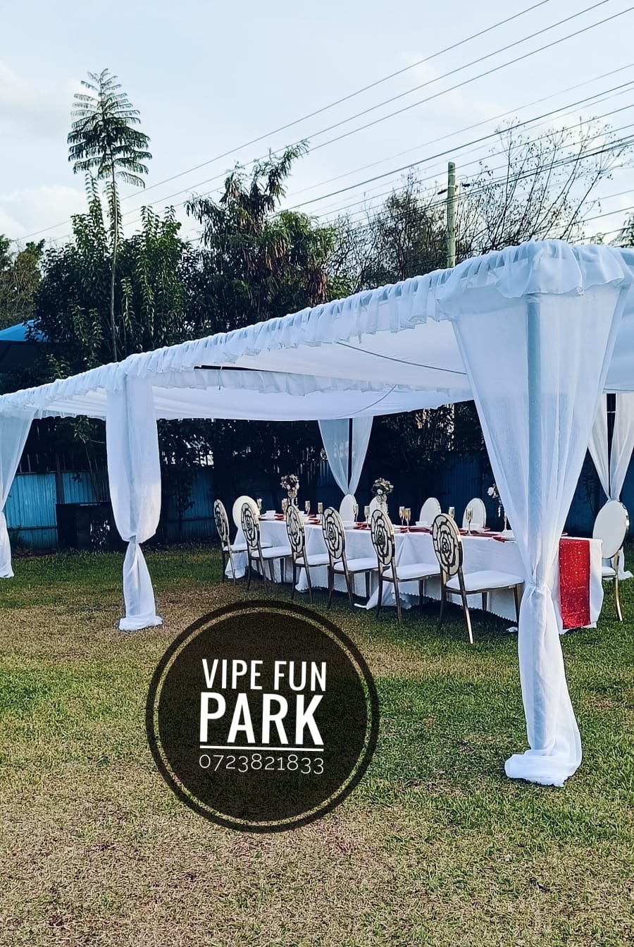 White stretch tent with ruffled draping over a styled head table and chairs on the lawn