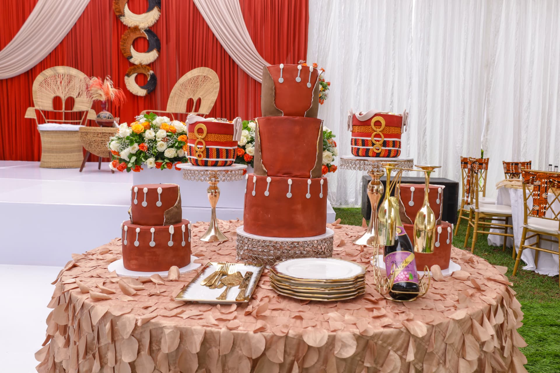 Traditional terracotta cake collection on gold stands with red and white celebration draping